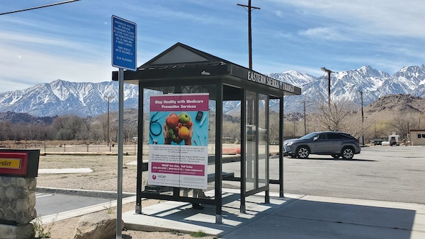 Eastern Sierra Transit's bus stop in Lone Pine with the snowcapped Sierra Nevada Mountains behind it.