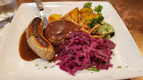 Danish combination plate with Danish Sausage, frikadeller, red cabbage, cucumber salad and roasted potatoes.