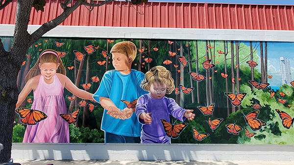 Colorful mural of three children surrounded by numerous orange and lack Monarch butterflies in the outskirts of the town of Lompoc.